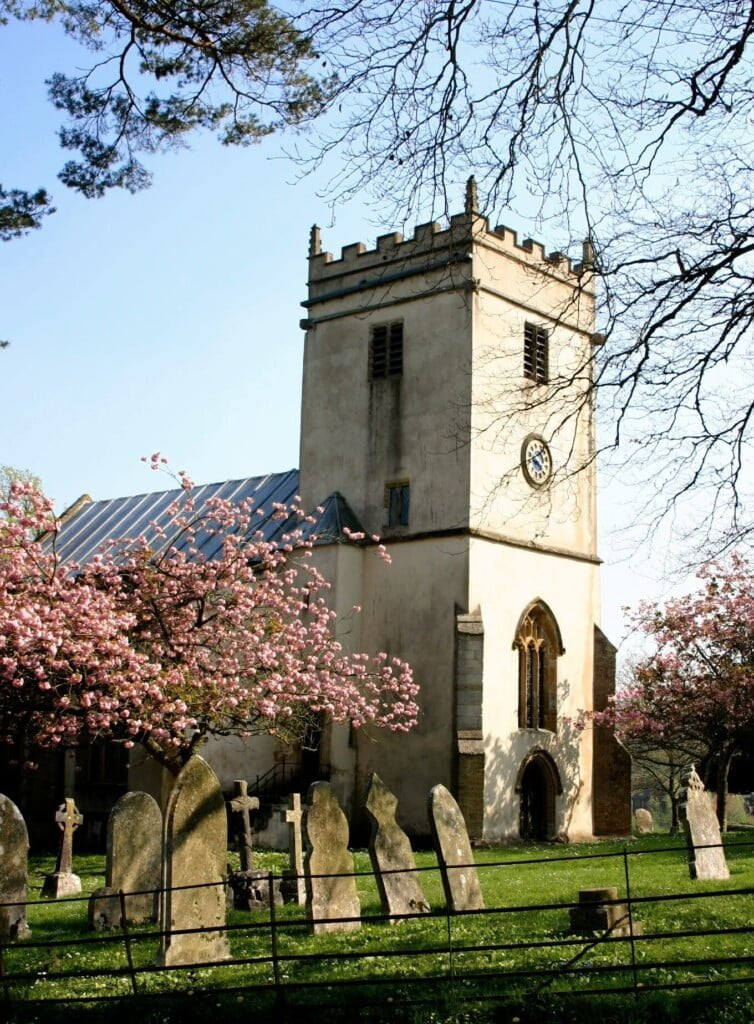 Buckland Newton Church tower with cherry blossom bloomimg