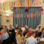 Assembled throng tucking in in Shipton Gorge Village Hall