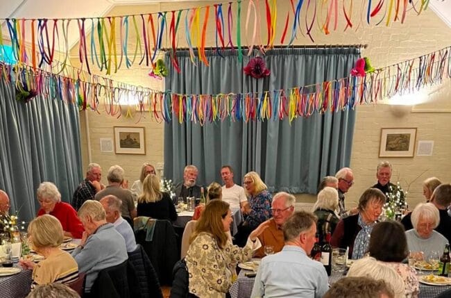 Assembled throng tucking in in Shipton Gorge Village Hall