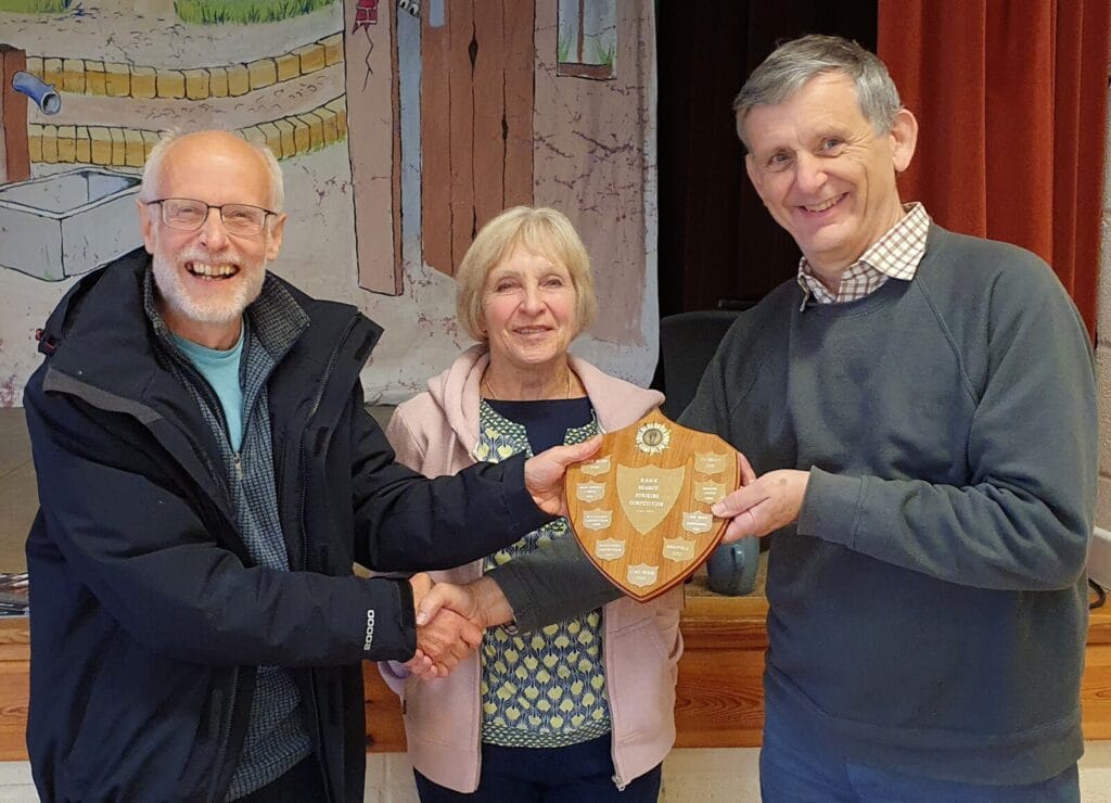 Evershot Tower Captain, Gareth Evans, being presented with the Striking Competition Shield by Judges, Sue Carter and Jonathan Godfrey